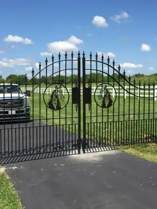 Custom ornamental driveway gate with horse head medallions, an arched top and pointed finials