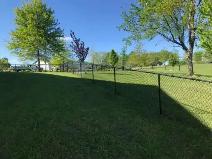 Black chain link fence running across a sprawling rural property
