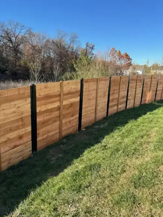 Modern horizontal cedar plank fence with black steel posts on a finished residential job