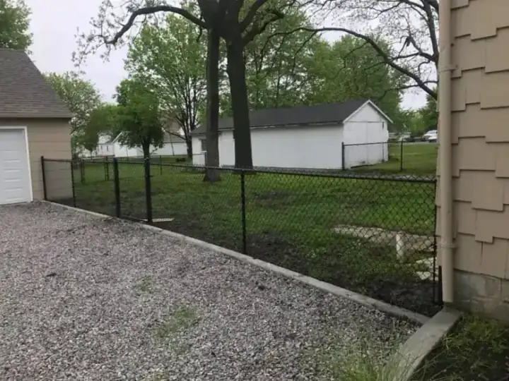 Black chain link fence in a residential yard by a garage