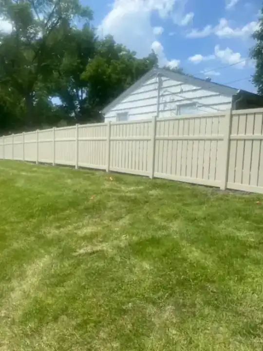 Tan vinyl privacy fence run beside a house