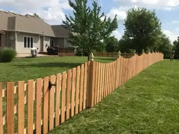 Scalloped top natural cedar picket fence along a front garden